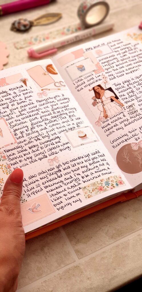 A tall narrow photo of a bullet journal containing images and text. A woman's hand is holding the pages open on the left hand side.